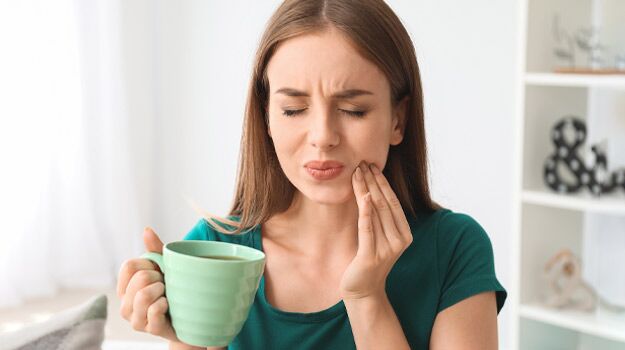 A Woman Suffering from Tooth Pain While Holding a Glass of Coffee